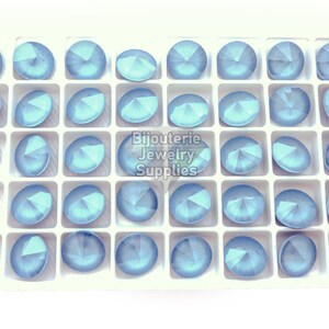 May include: A tray of 40 light blue round rhinestones in a white plastic tray. The rhinestones are arranged in a grid pattern. The tray has the text "Bijouterie Jewelry Supplies" printed on it.