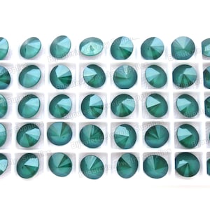May include: A sheet of 36 round, green, faceted rhinestones in a white plastic tray. The rhinestones are arranged in six rows of six. The tray has the text "Bijouterie Jewelry Supplies" printed on it.