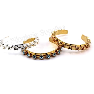 May include: Three bracelets, one silver and two gold, with spikes and blue rhinestones.