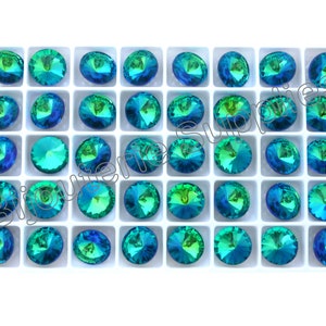 May include: A tray of 36 round, faceted, iridescent green and blue rhinestones. The rhinestones are arranged in a grid pattern.