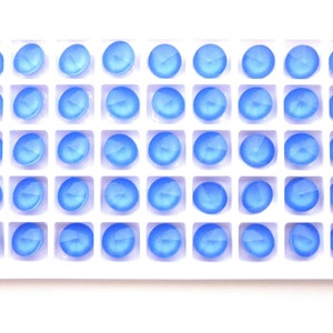 May include: A white plastic tray filled with 36 light blue round glass gems.