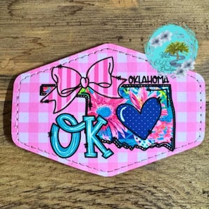 May include: Pink and white gingham fabric with a blue and white heart, a pink bow, and the words "OK" and "OKLAHOMA" in a blue and white font.
