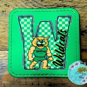 May include: A green patch with a stitched border featuring a cartoon wildcat mascot. The letter "W" is filled with a green and yellow checkered pattern. The word "Wildcats" is written in black script.