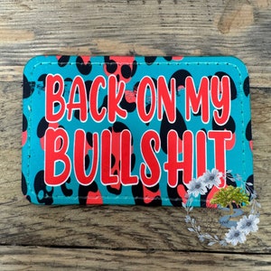 May include: A teal blue and black leopard print fabric patch with the text "BACK ON MY BULLSHIT" in red.