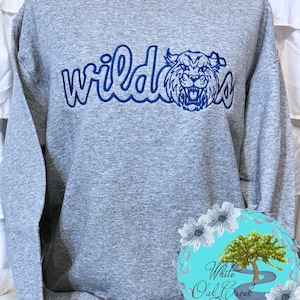 May include: A gray sweatshirt with the word "wildcats" in a blue script font and a blue wildcat graphic. The sweatshirt is a crew neck style.
