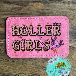May include: Pink leather patch with the text "HOLLER GIRLS" in brown letters with a western design. The patch has a pink cowgirl boot, a brown cowboy hat, and a brown horseshoe with a skull and crossbones.