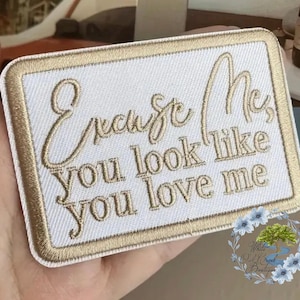 May include: Beige embroidered patch with the text "Excuse me, you look like you love me" in a cursive font.