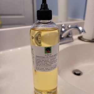 Puede incluir: Una botella de vidrio transparente con un gotero negro en la parte superior, llena de un l&iacute;quido amarillo. La etiqueta de la botella dice "O.M.G! Suero para el cabello con aceite esencial" y enumera los beneficios del suero, que incluyen promover el crecimiento del cabello, hidratar, fortalecer, prevenir la p&eacute;rdida de cabello, calmar el cuero cabelludo con picaz&oacute;n, prevenir el cuero cabelludo seco, ayudar con la inflamaci&oacute;n del cuero cabelludo y se puede usar como un tratamiento de aceite caliente.