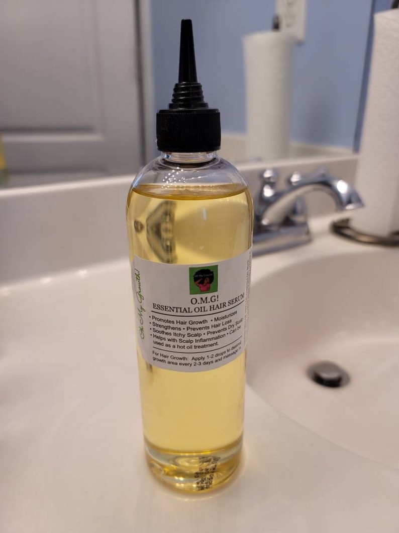 Puede incluir: Una botella de vidrio transparente con un gotero negro en la parte superior, llena de un l&iacute;quido amarillo. La etiqueta de la botella dice "O.M.G! Suero para el cabello con aceite esencial" y enumera los beneficios del suero, que incluyen promover el crecimiento del cabello, hidratar, fortalecer, prevenir la p&eacute;rdida de cabello, calmar el cuero cabelludo con picaz&oacute;n, prevenir el cuero cabelludo seco, ayudar con la inflamaci&oacute;n del cuero cabelludo y se puede usar como un tratamiento de aceite caliente.