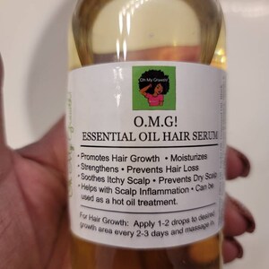 Puede incluir: Una botella de vidrio transparente con un l&iacute;quido amarillo en su interior. La botella tiene una etiqueta blanca con el texto "O.M.G! ESSENTIAL OIL HAIR SERUM" y una lista de beneficios, que incluyen promover el crecimiento del cabello, hidratar, fortalecer, prevenir la p&eacute;rdida de cabello, calmar el cuero cabelludo con picaz&oacute;n, prevenir el cuero cabelludo seco y ayudar con la inflamaci&oacute;n del cuero cabelludo. La etiqueta tambi&eacute;n indica que el suero se puede usar como un tratamiento de aceite caliente. La etiqueta indica aplicar 1-2 gotas en el &aacute;rea de crecimiento deseada cada 2-3 d&iacute;as y masajear.