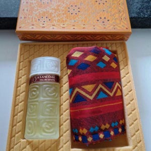 Könnte beinhalten: Ein Parfüm-Geschenkset mit einer Flasche Lancôme Eau de Toilette und einem gemusterten Schal. Das Set wird in einer dekorativen Box mit passendem Tablett präsentiert. Die Flasche ist klar mit einem weißen Verschluss.