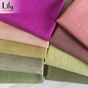 May include: A stack of eight different colored fabric swatches. The colors are pink, brown, green, yellow, light green, dark green, and purple. The fabric has a textured weave.