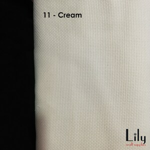Peut inclure: Tissu Aida de couleur cr&egrave;me avec une texture tiss&eacute;e. Le tissu est &eacute;tiquet&eacute; "11 - Cr&egrave;me" et porte le texte "Lily craft supplies" dans le coin inf&eacute;rieur droit.