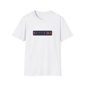 Puede incluir: Camiseta blanca con un gráfico colorido de sintaxis de código. El diseño presenta paréntesis, llaves y un símbolo de flecha, todo en una paleta vibrante de rosa, amarillo y azul.