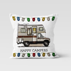 May include: White throw pillow featuring a vintage RV illustration. The RV is brown, white, and beige, with the text "HAPPY CAMPERS" below. A string of colorful owl-shaped lights decorates the top and bottom.