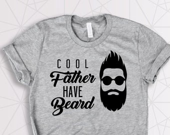 Puede incluir: Camiseta gris claro con un gráfico negro de un hombre con barba y gafas de sol. El texto "Cool Father Have Beard" está impreso en la camiseta.