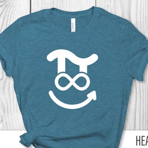 May include: A teal t-shirt with a white graphic of a Pi symbol, an infinity symbol, and a smiling face. The text "HEATHER DEEP TEAL" is printed on the shirt. The shirt is made of a soft material.