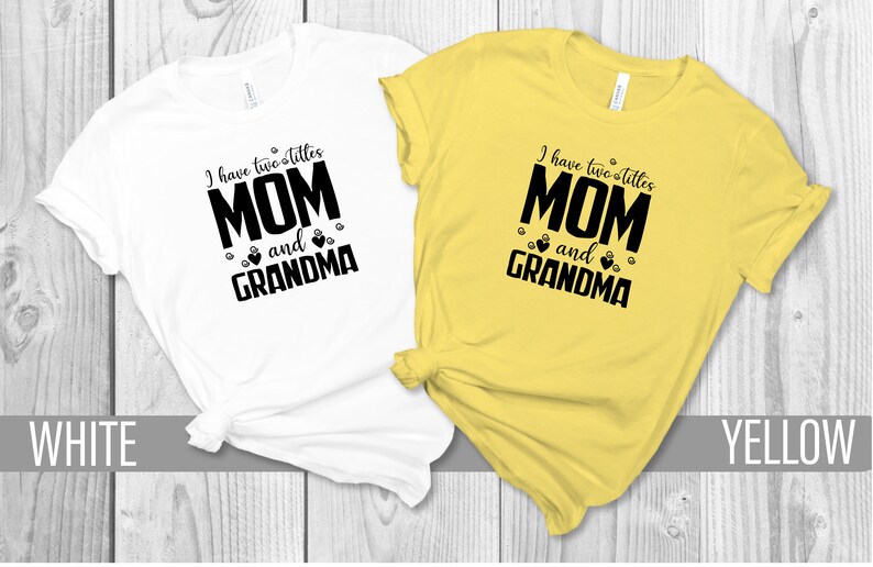 May include: Two t-shirts, one white and one yellow, with the text "I have two titles MOM and GRANDMA" printed in black. The text is surrounded by small paw prints and hearts.