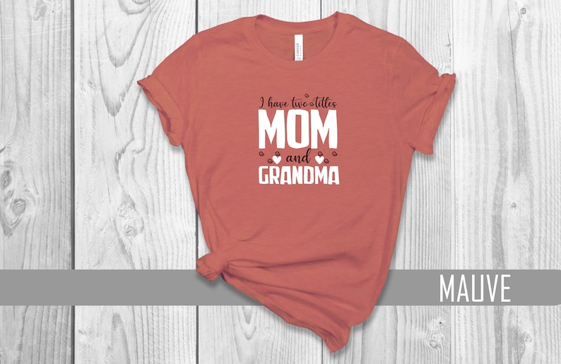 May include: A mauve t-shirt with the text "I have two titles MOM and GRANDMA" in white with black paw prints and hearts.