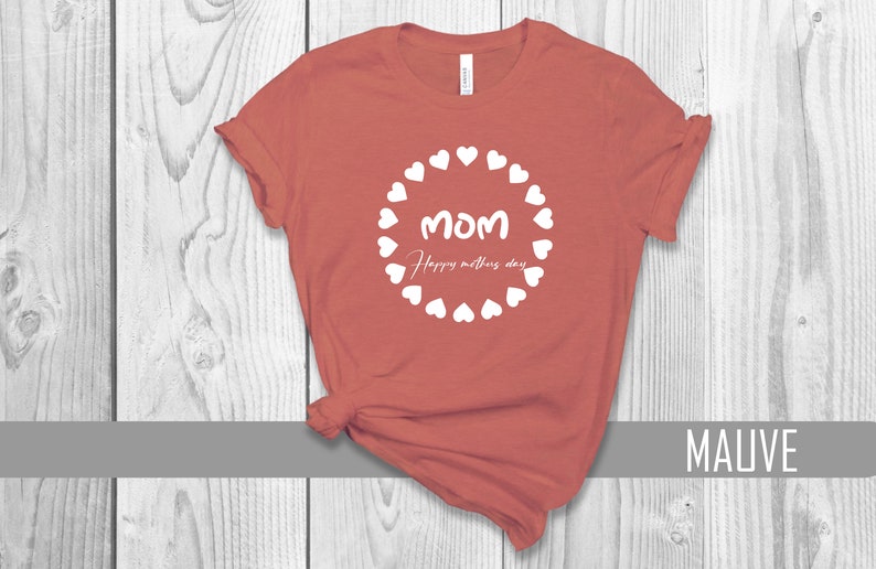 May include: A mauve t-shirt with a white circle design featuring the word "MOM" and the text "Happy Mother's Day" surrounded by white hearts.