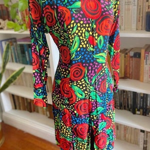 May include: A black dress with a colorful floral print featuring red roses, green leaves, and yellow, blue, and pink polka dots.