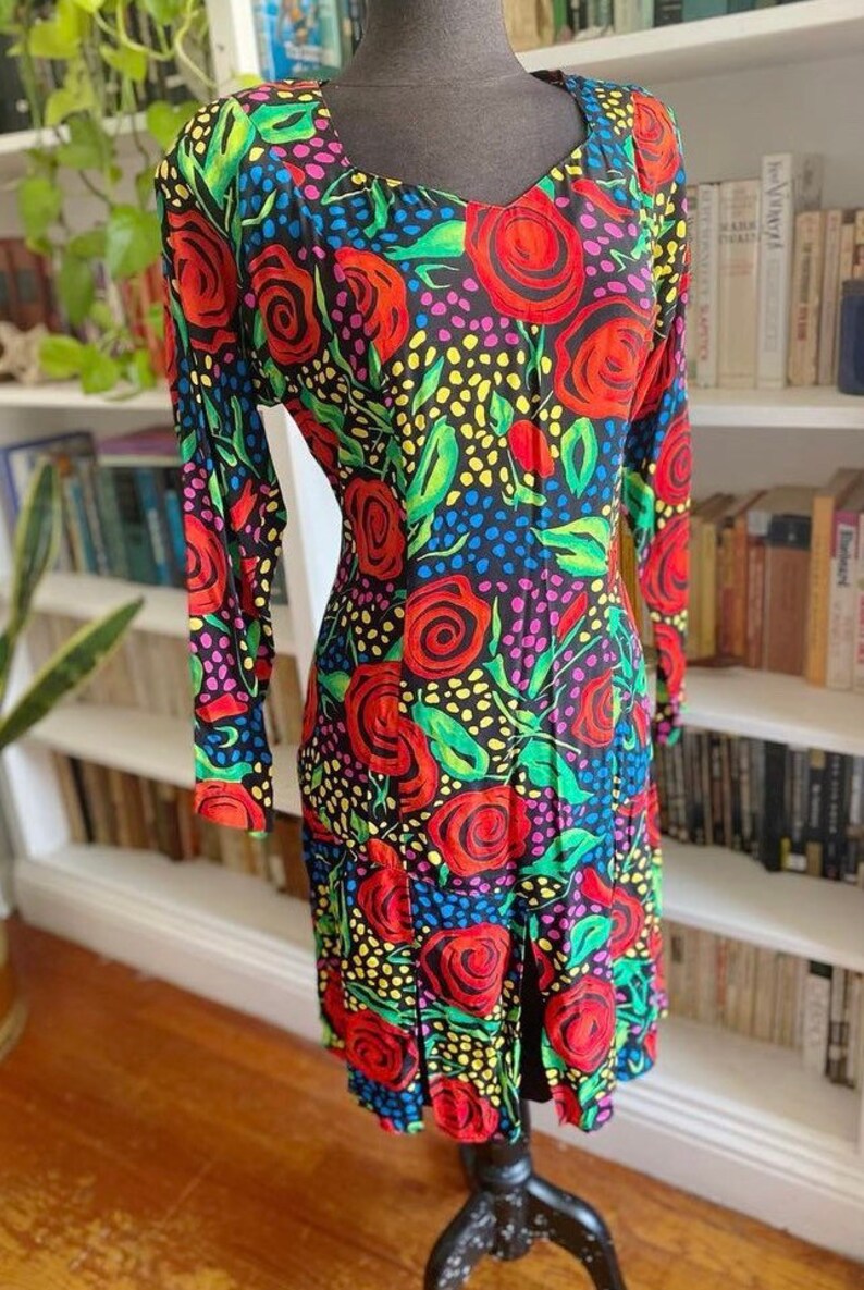 May include: A black dress with a colorful floral print featuring red roses, green leaves, and yellow, blue, and pink polka dots.