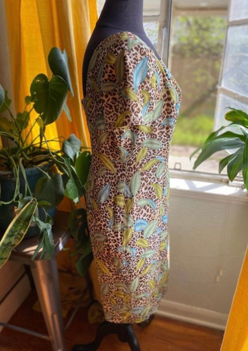 Puede incluir: Un vestido marr&oacute;n y blanco con un estampado de hojas verdes y azules. El vestido tiene una silueta ajustada y un escote cuadrado.