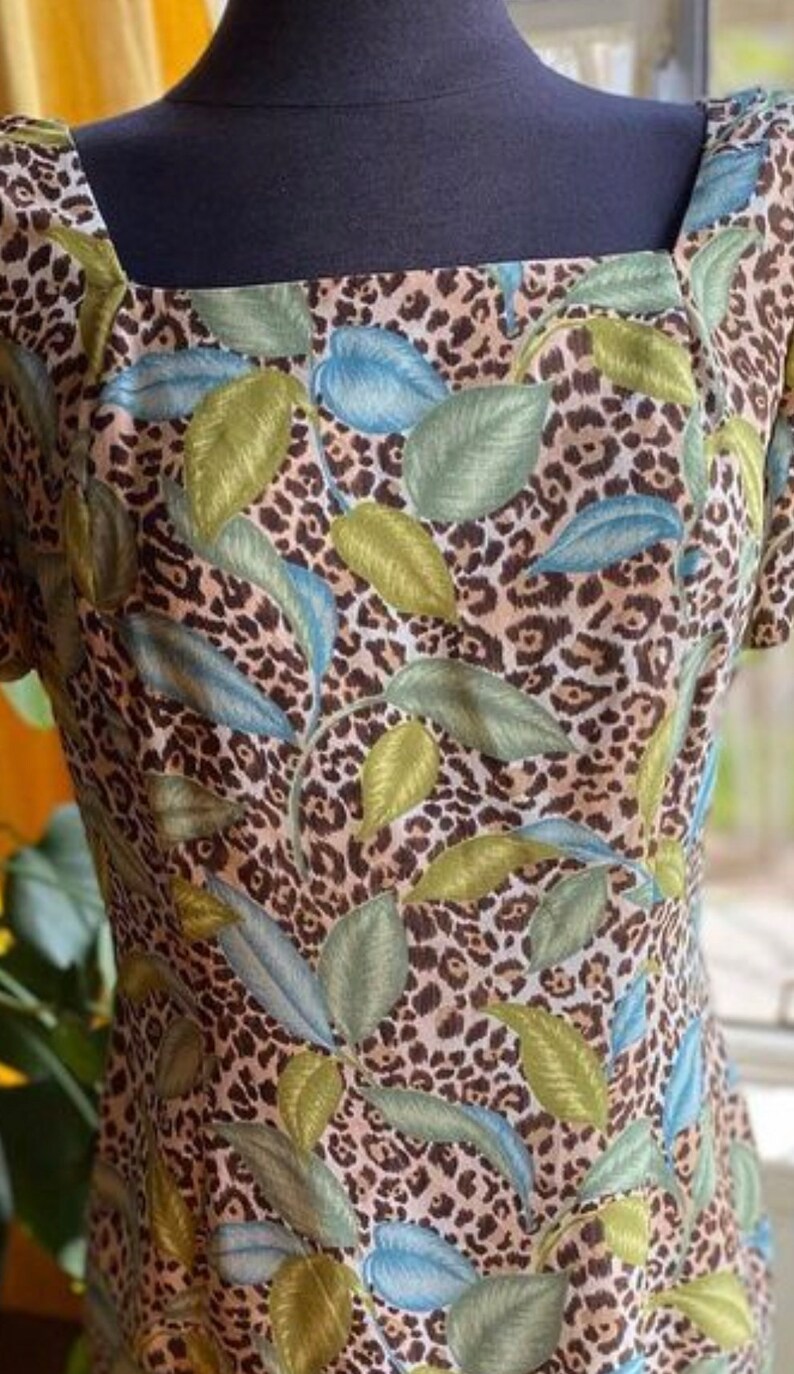 Puede incluir: Un vestido marr&oacute;n y blanco con estampado de leopardo y estampado floral verde y azul.