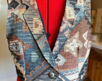 May include: A brown, blue, and beige patterned vest with a button closure. The vest has a pointed collar and a fitted silhouette.