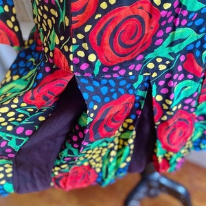 May include: A black dress with a colorful floral print featuring red roses, green leaves, and yellow, pink, and blue polka dots.