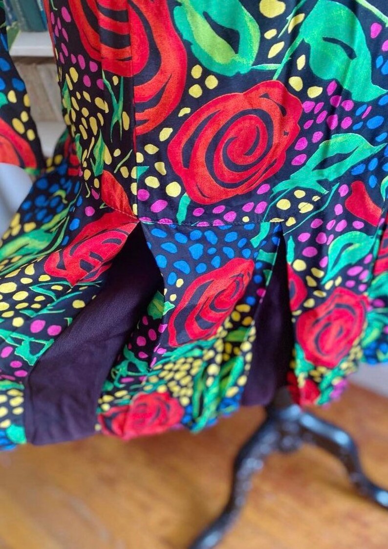 May include: A black dress with a colorful floral print featuring red roses, green leaves, and yellow, pink, and blue polka dots.