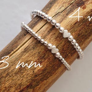 Op de afbeelding: Twee zilveren kralen armbanden met hartcharms. De armband bovenaan heeft 4 mm kralen en de armband onderaan heeft 3 mm kralen.