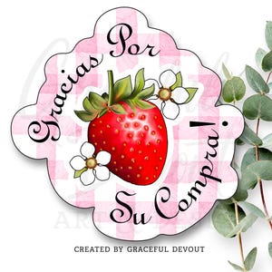 May include: A sticker with a red strawberry illustration, green leaves, and white flowers. The sticker has the text "Gracias Por Su Compra!" in black script on a pink and white checkered background. The text "CREATED BY GRACEFUL DEVOUT" is at the bottom.