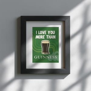 May include: Framed art print in a black frame. The print shows a pint of Guinness stout on a green background with the text "I LOVE YOU MORE THAN GUINNESS". Includes shamrock decorations.