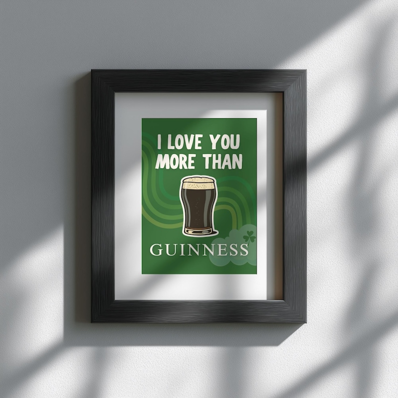May include: Framed art print in a black frame. The print shows a pint of Guinness stout on a green background with the text "I LOVE YOU MORE THAN GUINNESS". Includes shamrock decorations.