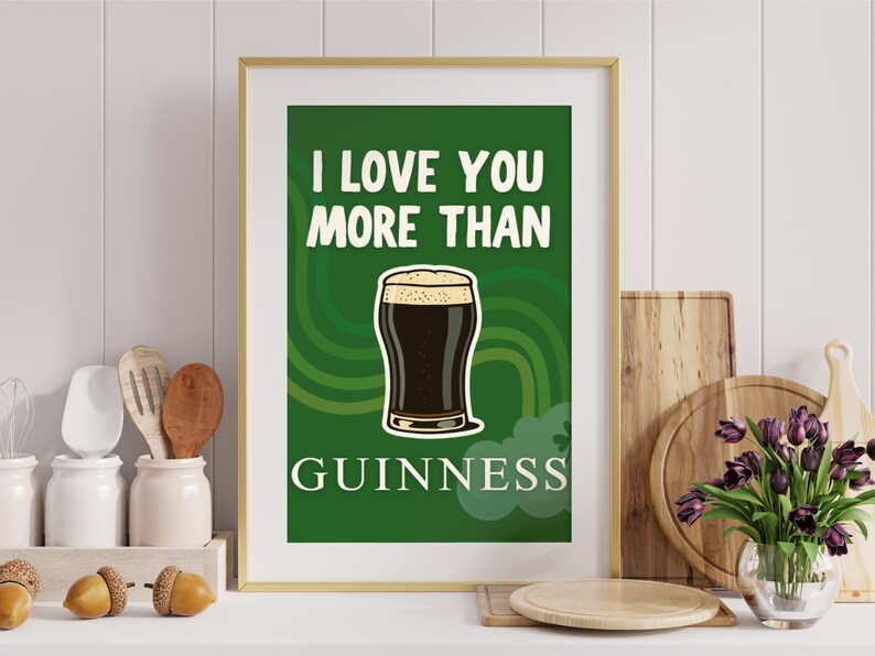 May include: A framed print featuring the words "I love you more than Guinness" above a pint of stout. The background is green with curved lines. The print is in a gold frame, suitable for a kitchen or bar.