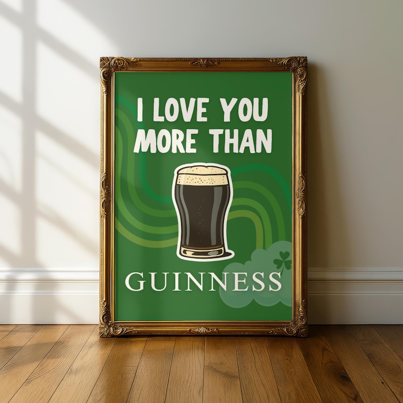 May include: Framed art print with a green background and gold ornate frame. The print features the text "I LOVE YOU MORE THAN GUINNESS" with a graphic of a pint of Guinness stout. A decorative piece for a bar or kitchen.