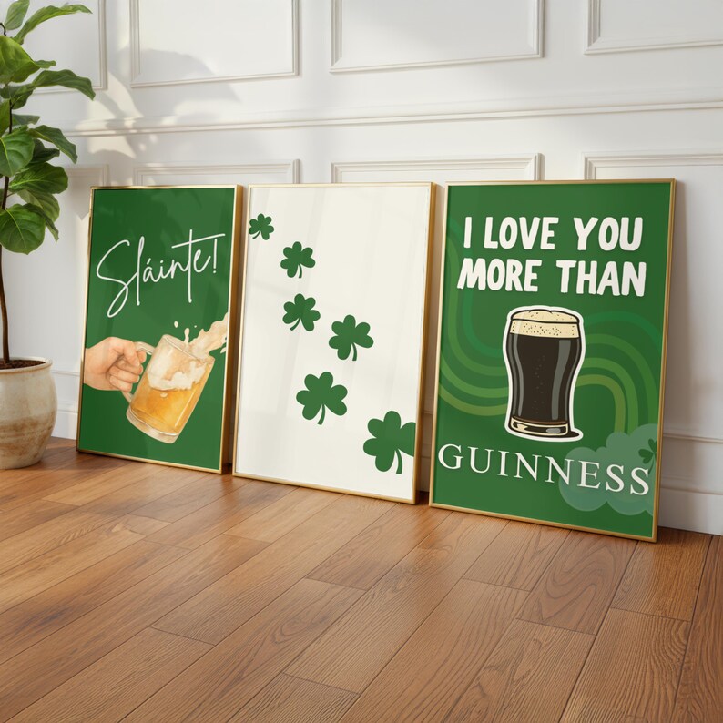 May include: Three framed art prints with gold frames. The prints feature St. Patrick's Day themes. One print says "Sl&aacute;inte!" with a beer mug. Another has shamrocks. The third says "I LOVE YOU MORE THAN GUINNESS".