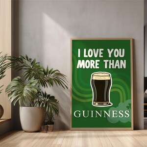 May include: A framed poster with the text "I LOVE YOU MORE THAN GUINNESS" on a green background. The poster features a cartoon pint of Guinness. The poster is in a room with plants and a window.