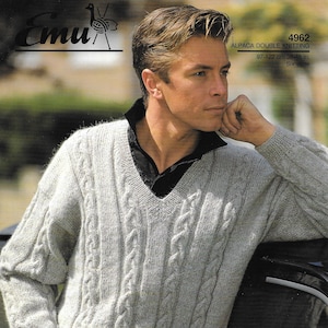 May include: A grey cable knit jumper with a V-neck. The jumper is made of alpaca wool and has a relaxed fit. The jumper is shown on a model wearing blue jeans. Emu Alpaca Double Knitting 4962 97-122 cm 38-48 in. Six sizes.