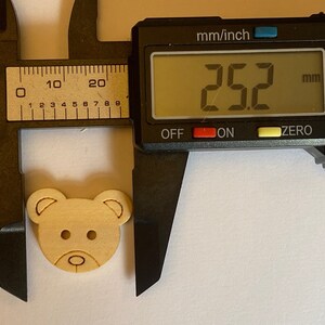 Pode incluir: Um bot&atilde;o de madeira em forma de urso com um di&acirc;metro de 6,4 cm. O bot&atilde;o &eacute; de cor castanho claro e tem um design simples.