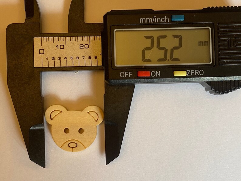 Pode incluir: Um bot&atilde;o de madeira em forma de urso com um di&acirc;metro de 6,4 cm. O bot&atilde;o &eacute; de cor castanho claro e tem um design simples.