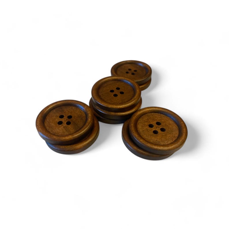 May include: A set of six brown wooden buttons, each with four holes. The buttons are arranged in a triangular shape.