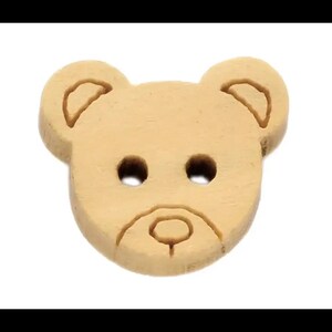 May include: A light brown, wooden button shaped like a teddy bear's face. The button features two eye holes and a stitched mouth. The ears have a stitched outline. Suitable for sewing and craft projects.