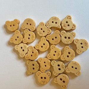 Pode incluir: Uma cole&ccedil;&atilde;o de 17 bot&otilde;es de madeira em forma de ursinhos de pel&uacute;cia. Os bot&otilde;es s&atilde;o de cor marrom claro e t&ecirc;m um design simples.