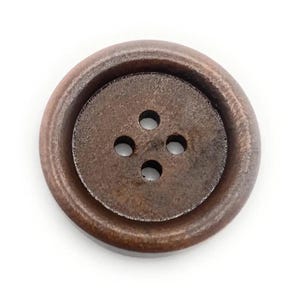 May include: A large, round, brown button with four holes. The button has a raised outer rim and a slightly textured surface. The colour is a warm, earthy brown, suitable for various sewing projects.