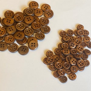 May include: A large pile of brown wooden buttons with four holes each. The buttons are arranged in a random pattern.