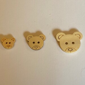 Pode incluir: Tr&ecirc;s bot&otilde;es de madeira em forma de urso em tamanhos diferentes. Os bot&otilde;es s&atilde;o de cor castanho claro e t&ecirc;m um design simples.