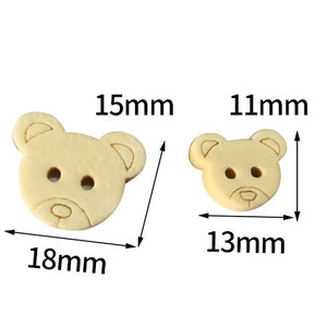Pode incluir: Dois bot&otilde;es de madeira em forma de urso. O bot&atilde;o maior mede 18 mm de largura e 15 mm de altura. O bot&atilde;o menor mede 13 mm de largura e 11 mm de altura.