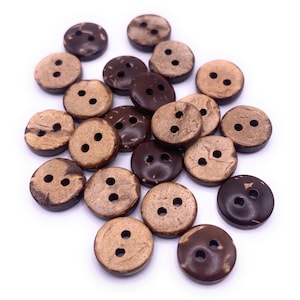 May include: A collection of brown and tan coconut shell buttons with two holes each. The buttons are scattered on a white background.